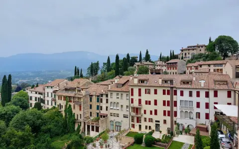 Asolo, cosa vedere: un borgo collinare con case in pietra, tetti rossi e giardini lussureggianti, incastonato tra le montagne.