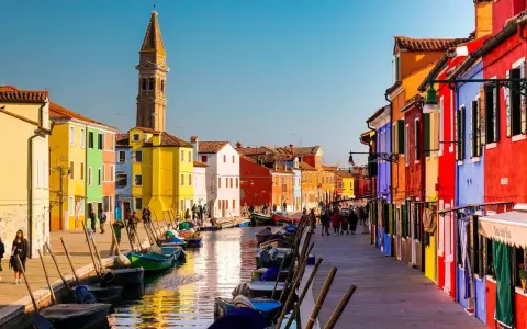 Coloratissima città lagunare con case vivaci, canali e barche ormeggiate.
