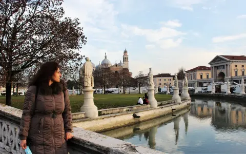 Donna guarda il canale con statue e palazzi a Padova, ideale per visite guidate.