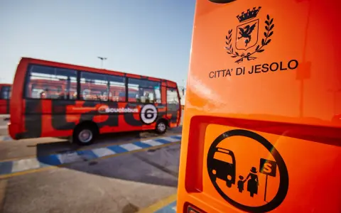 Autostazione Jesolo: scuolabus rosso con stemma "Città di Jesolo" e simbolo di fermata.