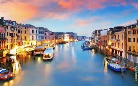 Il Canal Grande di Venezia, con le sue opere d'arte architettoniche illuminate al tramonto, accoglie gondole e vaporetti.