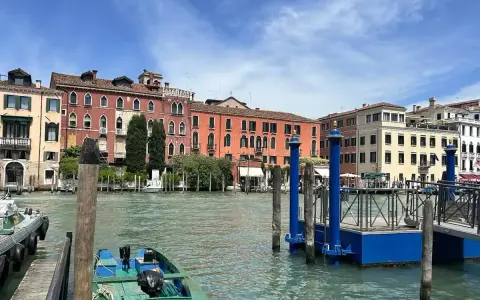 Canale di Venezia con edifici colorati e pontili blu. Per sapere how to get from Venice train station to San Marco, prendi un vaporetto.
