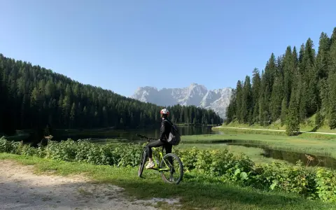 Ciclista ammira il panorama sul lago e le montagne lungo la ciclabile Auronzo Misurina.