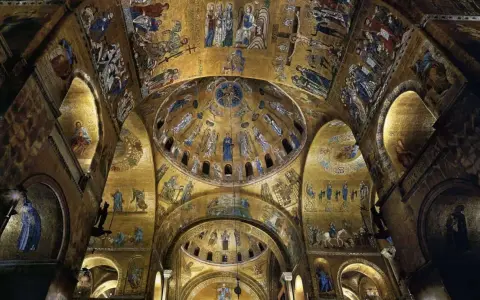 Interno dorato della Basilica di San Marco, con mosaici bizantini che adornano le volte e le cupole di San Marco, raffiguranti scene sacre e figure angeliche.