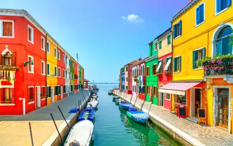 Coloratissima isola a Venezia, con case vivaci affacciate su un canale pieno di barche.