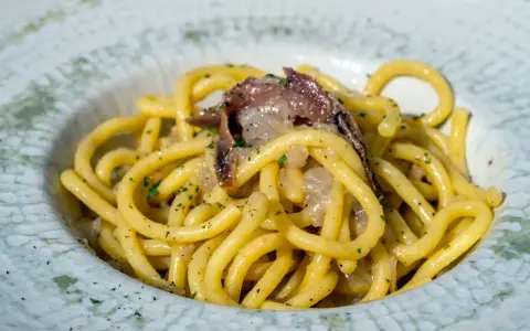 Spaghetti con acciughe e prezzemolo, un assaggio di cosa si mangia a Venezia. Un piatto semplice ma gustoso, perfetto per un pranzo veloce.