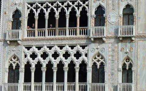 Dettaglio del **Palazzo Cadoro** con le sue finestre a trifora e balconi ornati. Persone osservano dal primo piano.