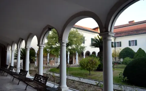 Portico con archi e colonne bianche, panchine e un giardino interno. Per sapere isola degli armeni come arrivare, visita questo luogo tranquillo.
