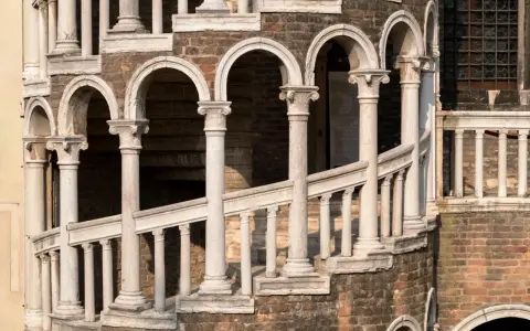 La scala Contarini a Venezia, con i suoi archi e colonne in marmo bianco, si snoda su una struttura in mattoni rossi, un'elegante spirale nel tempo.