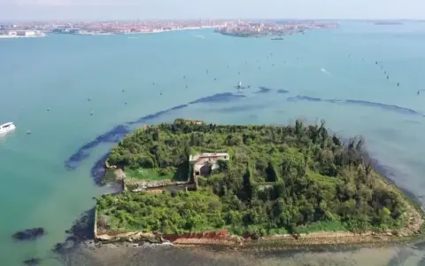 Un'isola verdeggiante con ruderi antichi, circondata da acque azzurre. Venezia è un'isola, e questa vista aerea ne mostra la bellezza selvaggia.