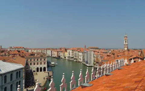 Vista dall'alto dei tetti rossi di Venezia, con il Canal Grande e le sue calli animate.