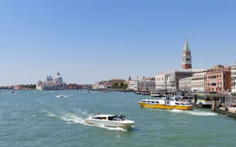 Venezia: il Canal Grande con la linea 1 vaporetto venezia fermate, barche e palazzi storici sotto un cielo azzurro.