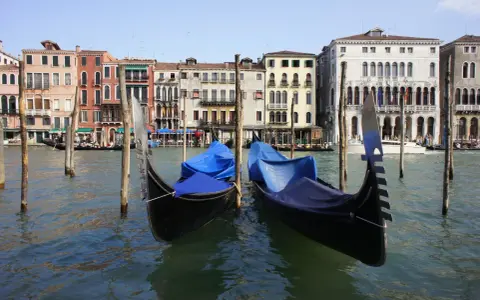 Gondole ormeggiate sul Canal Grande, pronte per le escursioni a Venezia. Edifici storici sullo sfondo.