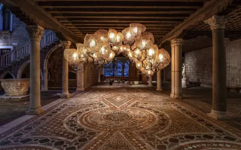 Interni Ca' d'Oro: un lampadario scenografico illumina il cortile con pavimenti a mosaico e colonne antiche.