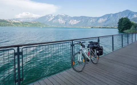 Bicicletta da turismo pronta per esplorare le ciclabili Dolomiti, con un lago azzurro e montagne maestose sullo sfondo.