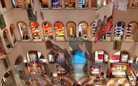 Interno del Fondaco dei Tedeschi, con archi, negozi e grandi stampe appese.