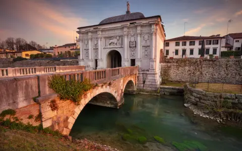 Porta San Tomaso a Treviso, un'idea per cosa fare a Treviso nel weekend. Un ponte in mattoni attraversa un canale con acqua verde.