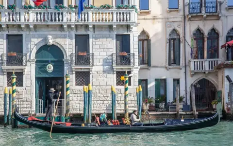 Gondola con gondoliere e passeggeri naviga lungo un canale a Venezia. Esplorare Venezia a piedi è un'esperienza, ma una gondola offre una prospettiva unica.