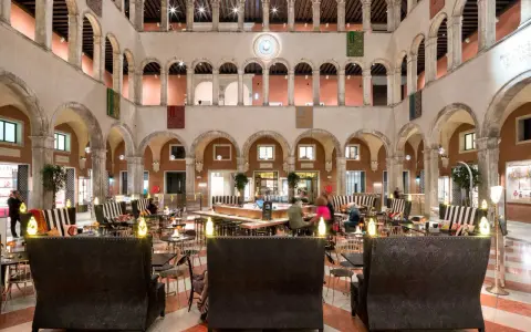 Lussuoso cortile interno con arcate, ideale per scoprire dove fare shopping a Venezia, tra negozi eleganti e aree lounge.