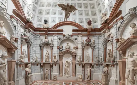 Interno del Palazzo Grimani a Venezia, un tripudio di sculture classiche e busti antichi che adornano nicchie e mensole, creando un'atmosfera di maestosa antichità.