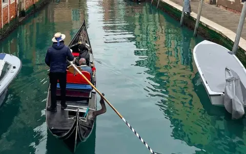 Gondola con gondoliere e passeggeri naviga in un canale veneziano vicino al park sant'andrea venezia.
