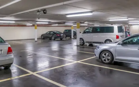 Parcheggio sotterraneo con diverse auto, tra cui un furgone bianco e una berlina nera. Un'auto argentata è in primo piano. Questo è l'ingresso a Venezia per chi arriva in auto.