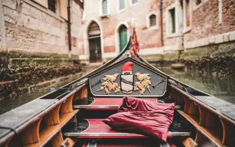 Gondola con cuscino rosso, pronta per un giro romantico a Venezia, città dell'amore.