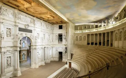 Interno del Teatro Olimpico, gioiello architettonico di una città veneta, con statue, colonne e un soffitto affrescato.