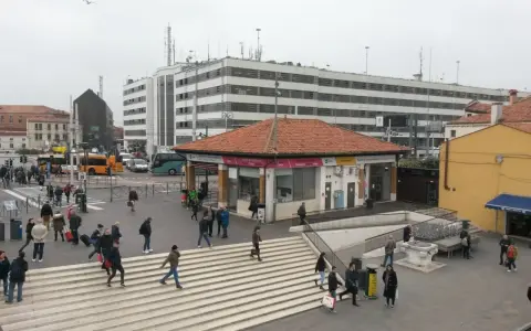 Persone attraversano le scale a Piazzale Roma, vicino a una fermata del vaporetto.