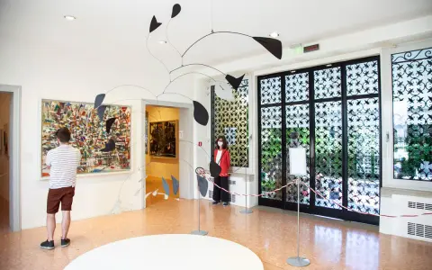 Un uomo ammira un quadro astratto, mentre una donna osserva una scultura mobile. Un'atmosfera d'arte al Peggy Guggenheim di Venezia.