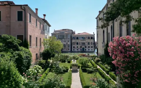 Giardini segreti a Venezia, con un canale e palazzi storici sullo sfondo. Un'oasi di pace tra il verde e i fiori.