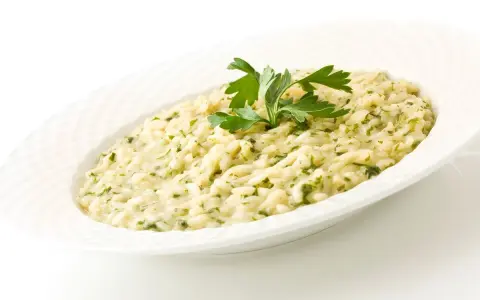 Risotto cremoso con prezzemolo, un piatto che evoca i sapori del mare di Venezia.