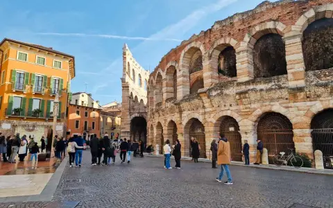 L'arena di Verona interno, con la sua maestosa struttura in pietra e archi, fa da sfondo a una piazza animata da turisti.