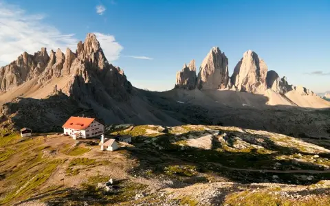 Rifugio con tetto rosso e montagne imponenti, un'oasi di pace tra i rifugi Dolomiti Bellunesi facili, ideale per un'escursione panoramica.