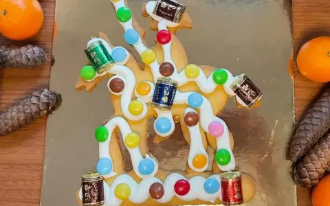 San Martino, dolce veneziano: biscotto decorato con glassa bianca, caramelle colorate e piccoli cioccolatini a forma di botte, su sfondo dorato.