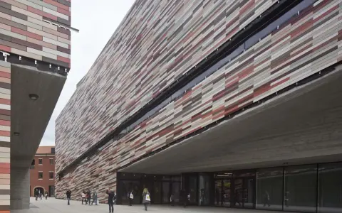 Il museo M9 a Mestre, con la sua facciata a listelli colorati, accoglie visitatori sotto un'imponente pensilina in cemento.