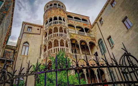 La scala chiocciola di Venezia, con i suoi archi e balconi, si erge maestosa tra antichi palazzi.