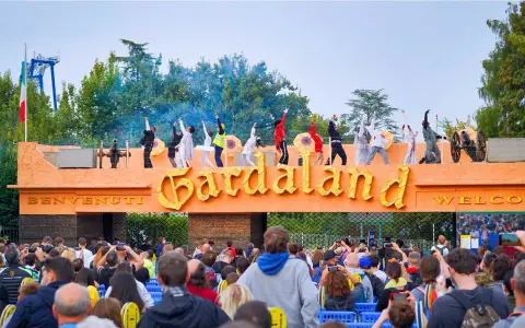 L'emozione di arrivare da Verona a Gardaland: artisti danzano sull'ingresso mentre la folla attende l'avventura.