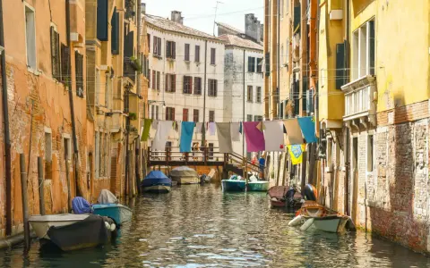 Angoli nascosti di Venezia: un canale tranquillo con barche ormeggiate e panni stesi ad asciugare tra case colorate.