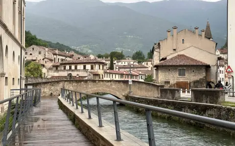 Passeggiata lungo il canale, tra antichi palazzi e ponti in pietra. Ecco cosa vedere a Vittorio Veneto, con le montagne sullo sfondo.