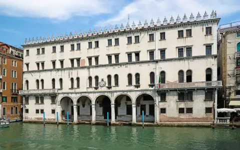 Palazzo sul Canal Grande, un tempo sede dei mercanti tedeschi, con le sue arcate e finestre che riflettono l'acqua di Venezia.