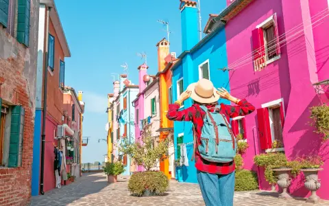 Una turista ammira le case colorate di Burano, un'isola raggiungibile con i traghetti da Chioggia.