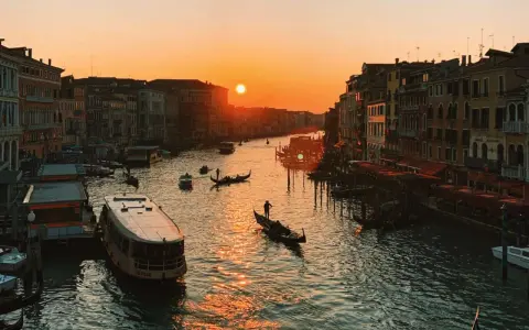 Tramonto sul Canal Grande, con gondole e vaporetti. Un'immagine da uno dei tanti punti panoramici di Venezia, con il sole che illumina l'acqua.