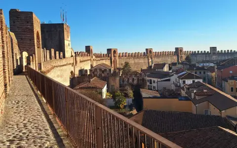 Passeggiata sulle mura della **cittadella** di Padova, con vista sui tetti e le torri medievali sotto un cielo azzurro.
