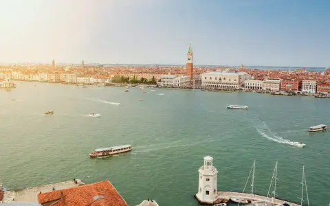 Vista aerea di Venezia con il Canal Grande, imbarcazioni e la famosa arte della città sullo sfondo.
