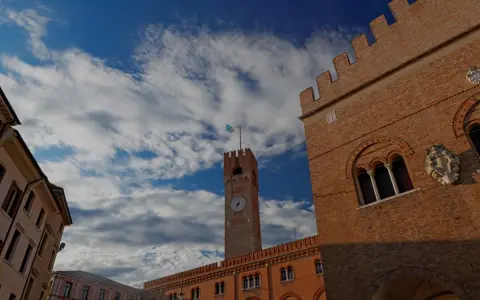 Torre dell'Orologio e palazzi storici a Treviso, un viaggio da Padova a Treviso sotto un cielo azzurro e nuvoloso.