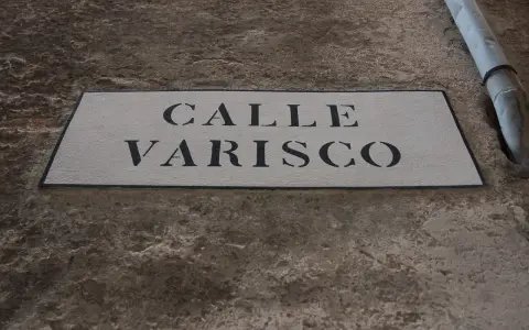 Targa in pietra con scritta "CALLE VARISCO" a Venezia, incastonata in un muro grezzo.