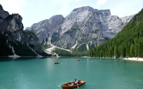 Lago turchese con barche a remi e maestose montagne veneto sullo sfondo.