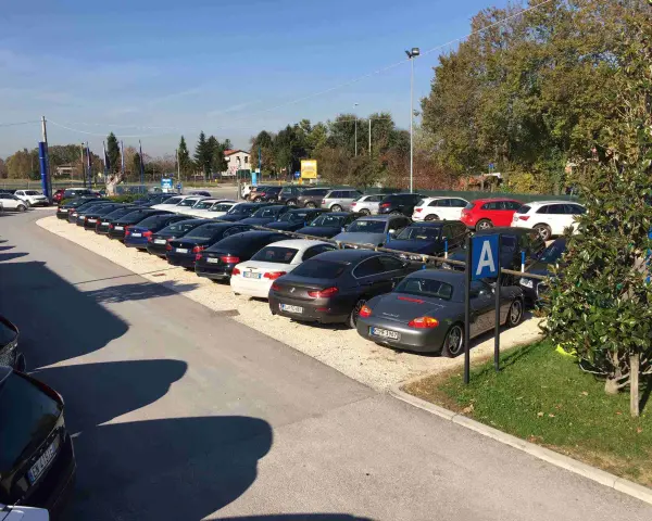 Parcheggio con auto moderne, forse vicino a Venezia Mestre o Santa Lucia. Un cartello blu con la "A" indica un'area di sosta.
