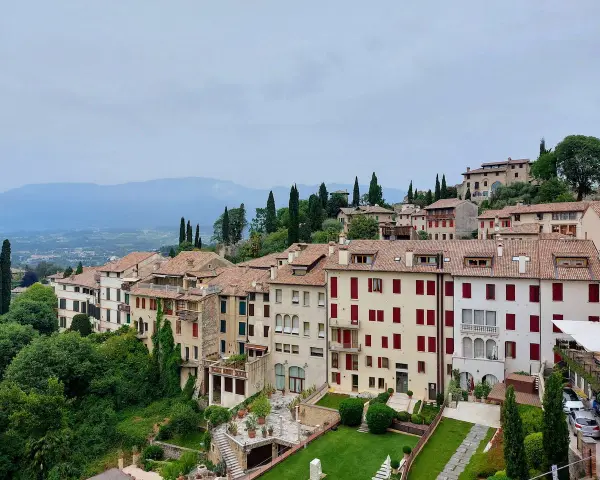Asolo, cosa vedere: un borgo collinare con case in pietra, tetti rossi e giardini lussureggianti, incastonato tra le montagne.